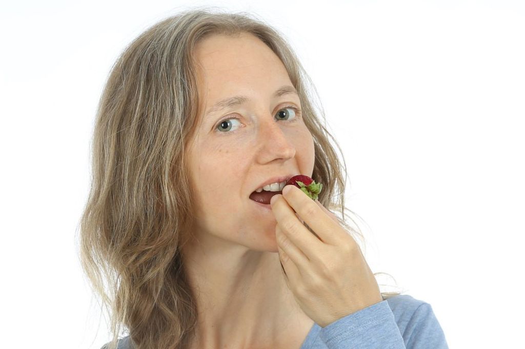 Eine Frau isst eine Erdbeere.